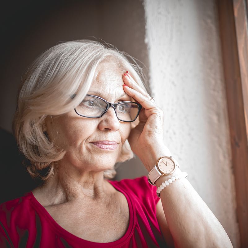Concerned senior woman looking out of a window Concerned senior woman looking out of a window